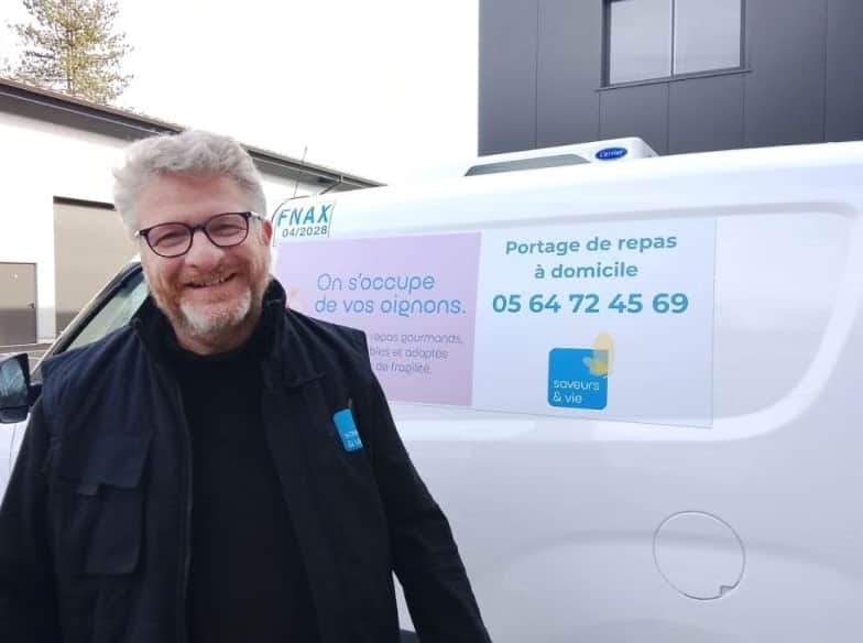Un membre de l’équipe Saveurs & Vie Bordeaux devant le véhicule de portage de repas de l’agence